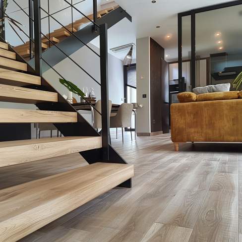 Living room moderne avec montée d'escalier et sol en lames de PVC clipsables aspect chêne gris